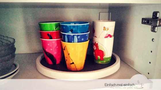 Colorful kids cups arranged on a Lazy Susan in a cupboard.